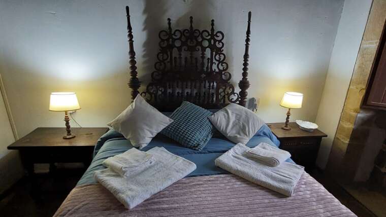 Dormitorio con cama de matrimonio y cabecero antiguo en casa rural Cantabria