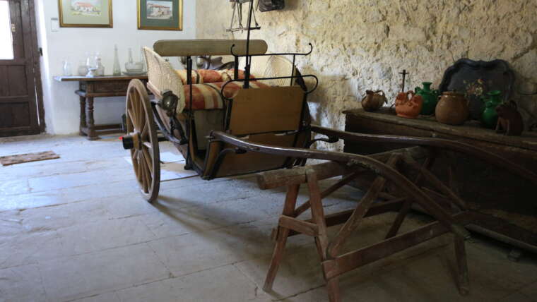 Espacio interior tradicional de La Casona de Cabanzón con carro antiguo