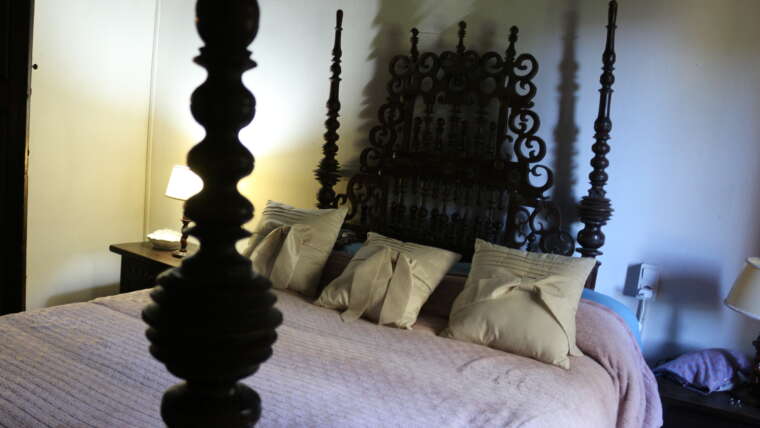 Habitación con cama y cabecero tradicional de forja en La Casona de Cabanzón