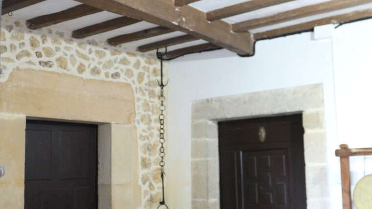 Entrada interior con vigas de madera y muros de piedra en La Casona de Cabanzón